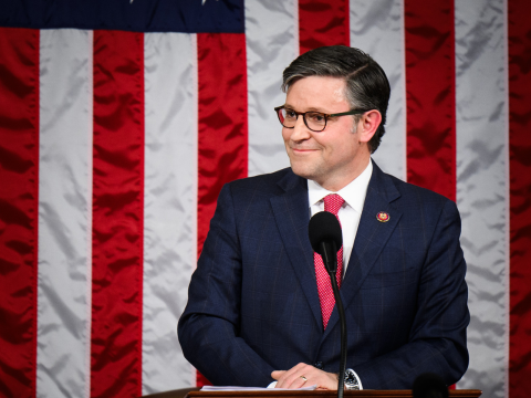 Speaker Mike Johnson stands in front of the American flag at the Speaker's dais as he is sworn in as Speaker.