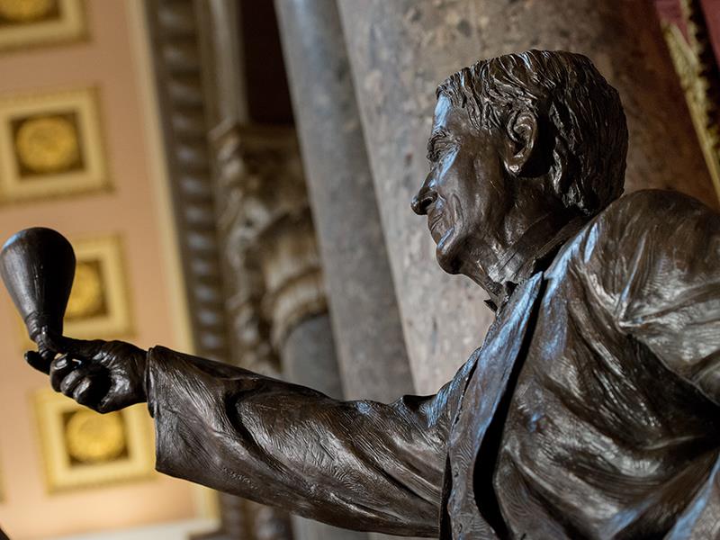 A bronze statue of Edison holding up an incandescent lightbulb